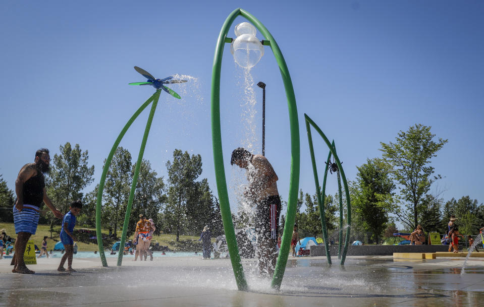 FILE - In this Wednesday, June 30, 2021 file photo, a man stands under a water feature trying to beat the heat at a splash park in Calgary, Alberta. Scientists say there’s something different this year from the recent drumbeat of climate weirdness. This summer a lot of the places hit by weather disasters are not used to getting extremes and many of them are wealthier, which is different from the normal climate change victims. That includes unprecedented deadly flooding in Germany and Belgium, 116-degree heat records in Portland, Oregon and similar blistering temperatures in Canada, along with wildfires. Now Southern Europe is seeing scorching temperatures and out-of-control blazes too. And the summer of extremes is only getting started. Peak Atlantic hurricane and wildfire seasons in the United States are knocking at the door. (Jeff McIntosh/The Canadian Press via AP, FIle)