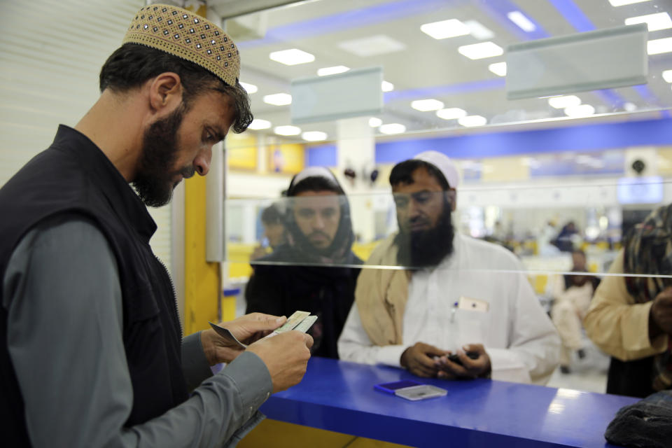 A worker checks the documents of a man to receive his passport in the main post office in the city of Kabul, Afghanistan, Wednesday, July 3, 2024. In parts of Afghanistan where there are no street names or house numbers, utility companies and their customers have adopted a creative approach for connecting. They use mosques as drop points for bills and cash, a "pay and pray" system. (AP Photo/Siddiqullah Alizai)