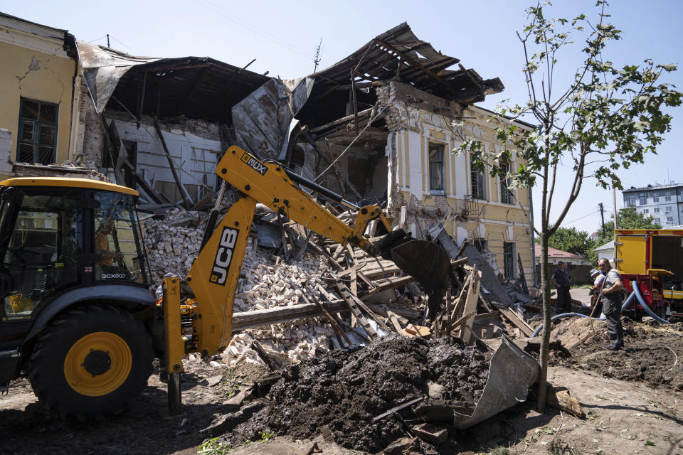 An excavator clear the rubble of military registration office destroyed by Russian attack in Kharkiv, Ukraine, Wednesday, July 6, 2022. (AP Photo/Evgeniy Maloletka)