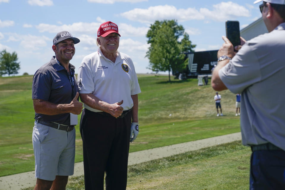 Former President Donald Trump, right, poses for a photo on the driving range before the second round of the LIV Golf Invitational tournament in Bedminster, N.J., Saturday, July 30, 2022. (AP Photo/Seth Wenig)