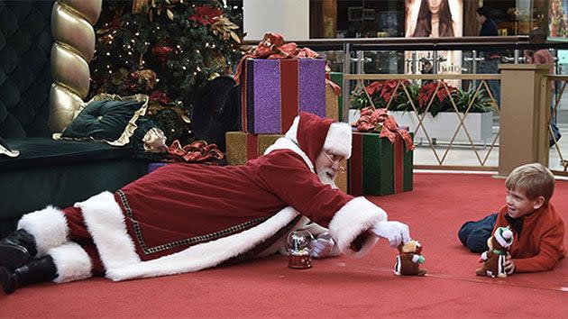 Santa creeped down on to the floor and began playing with the stuffed animal he brought for Brayden. Photo: Facebook