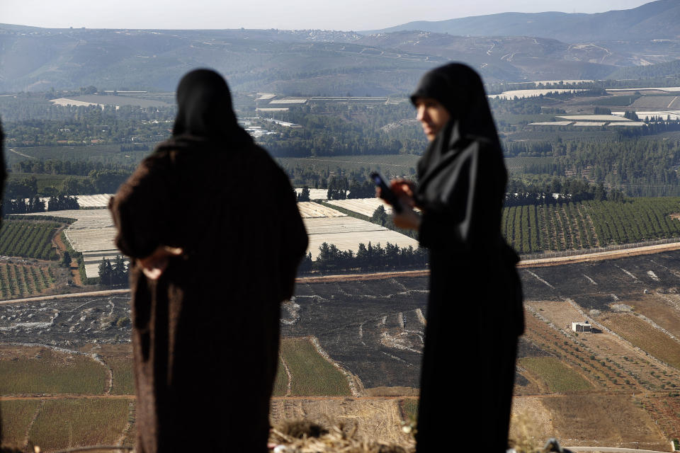 Lebanese villager women check their fields that burned on Sunday by the Israeli army shells, in the southern Lebanese border village of Maroun el-Ras, Lebanon, Monday, Sept. 2, 2019. Hezbollah militants on Sunday fired a barrage of anti-tank missiles into Israel, prompting a reprisal of heavy Israeli artillery fire in a rare burst of fighting between the bitter enemies.(AP Photo/Hussein Malla)