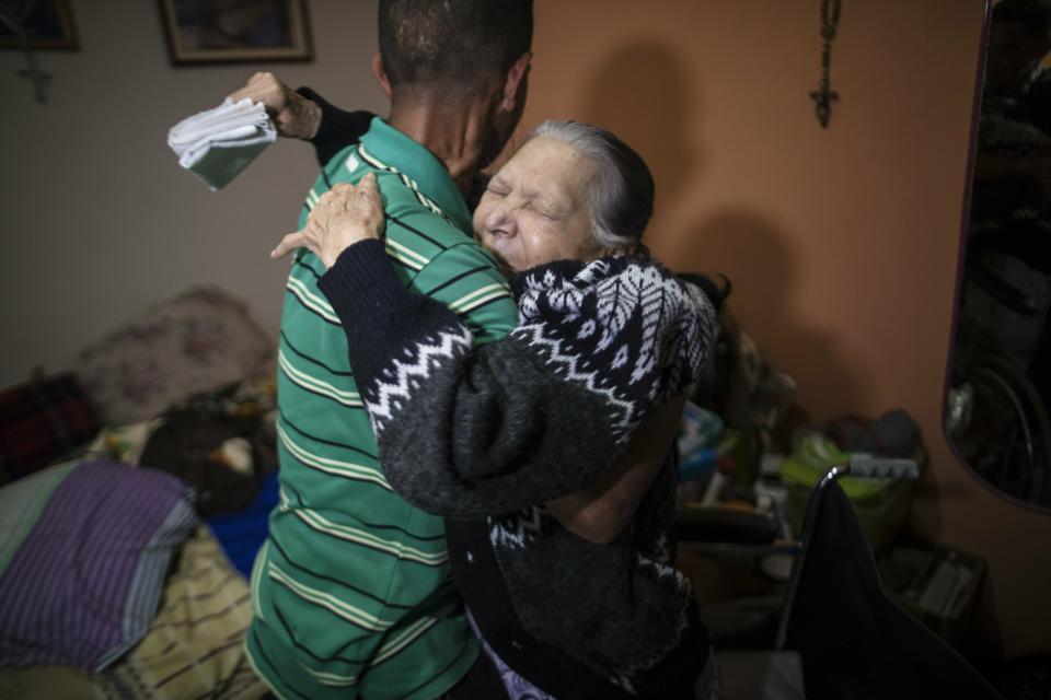 In this Feb. 4, 2019 photo, diabetes patient Aminta Villamizar, 83, is lifted into her bed by her grandson Antonio, in Caracas, Venezuela. Villamizar, a retired cleaning woman, has lost her right leg and two toes on her left one because she can’t find enough insulin to stave off diabetes. (AP Photo/Rodrigo Abd)