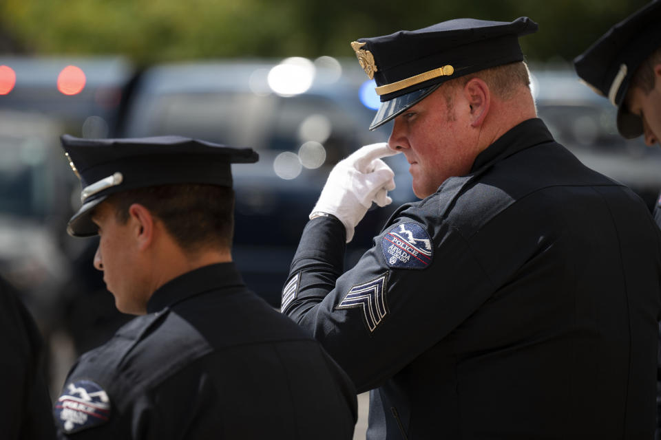 An Arvada Police officer wipes his eye as the hearse carrying fellow and fallen Officer Dillon Vakoff leaves the church parking lot after his memorial service on Friday, Sept. 16, 2022, at Flatirons Community Church in Lafayette, Colo. Vakoff was fatally shot while trying to break up a large family disturbance earlier in the week, in Arvada. (Timothy Hurst/The Gazette via AP)