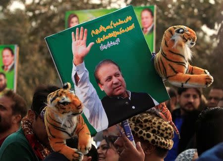 FILE PHOTO: A supporter of the ruling Pakistan Muslim League (Nawaz) (PML-N) holds a picture of Nawaz Sharif outside the accountability court where he appeared to face corruption charges filed against him, in Islamabad, Pakistan November 3, 2017. REUTERS/Faisal Mahmood/File Photo