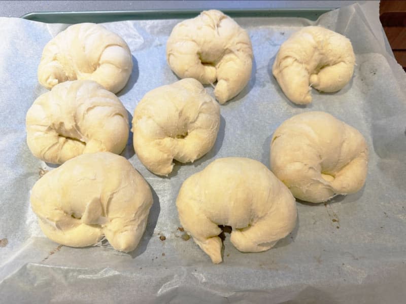 Raw croissants on a baking sheet with parchment paper