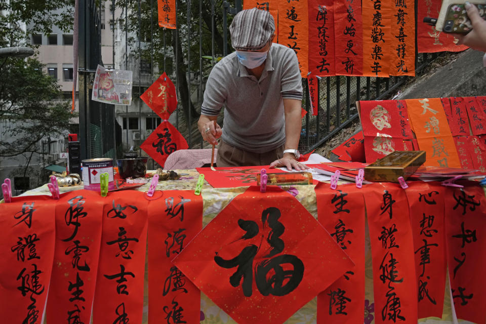 Derek Chan, a calligraphy artist, writes "Fai Chun," traditional decorations using Chinese calligraphy in Hong Kong on Jan. 26, 2022. In the runup to the Lunar New Year, calligraphers set up on the streets of Hong Kong to write ink-brush phrases on traditional red paper banners for homes and offices. (AP Photo/Kin Cheung)