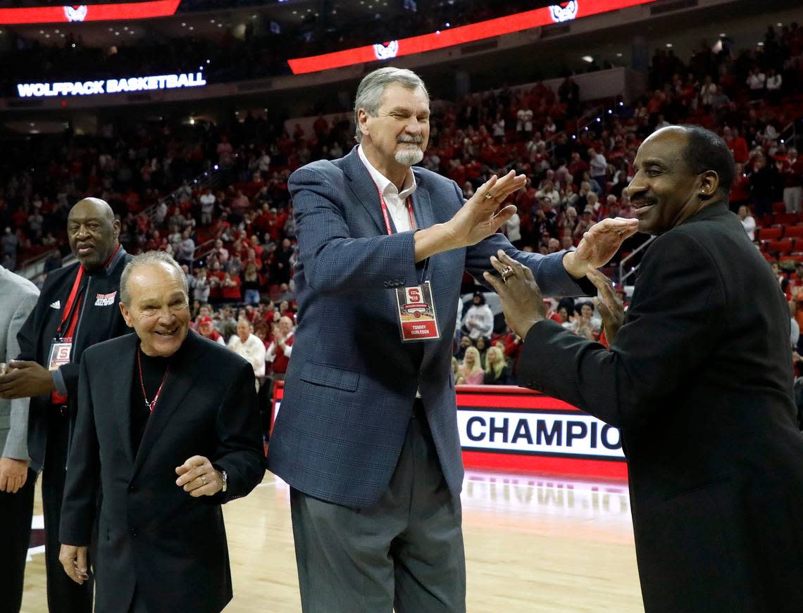 Monte Towe, left, smiles as Tommy Burleson and David Thompson acknowledge one another during a halftime ceremony to honor members of the N.C. State men’s basketball 1974 national championship team on Saturday, Feb. 24, 2024, at PNC Arena in Raleigh, N.C.