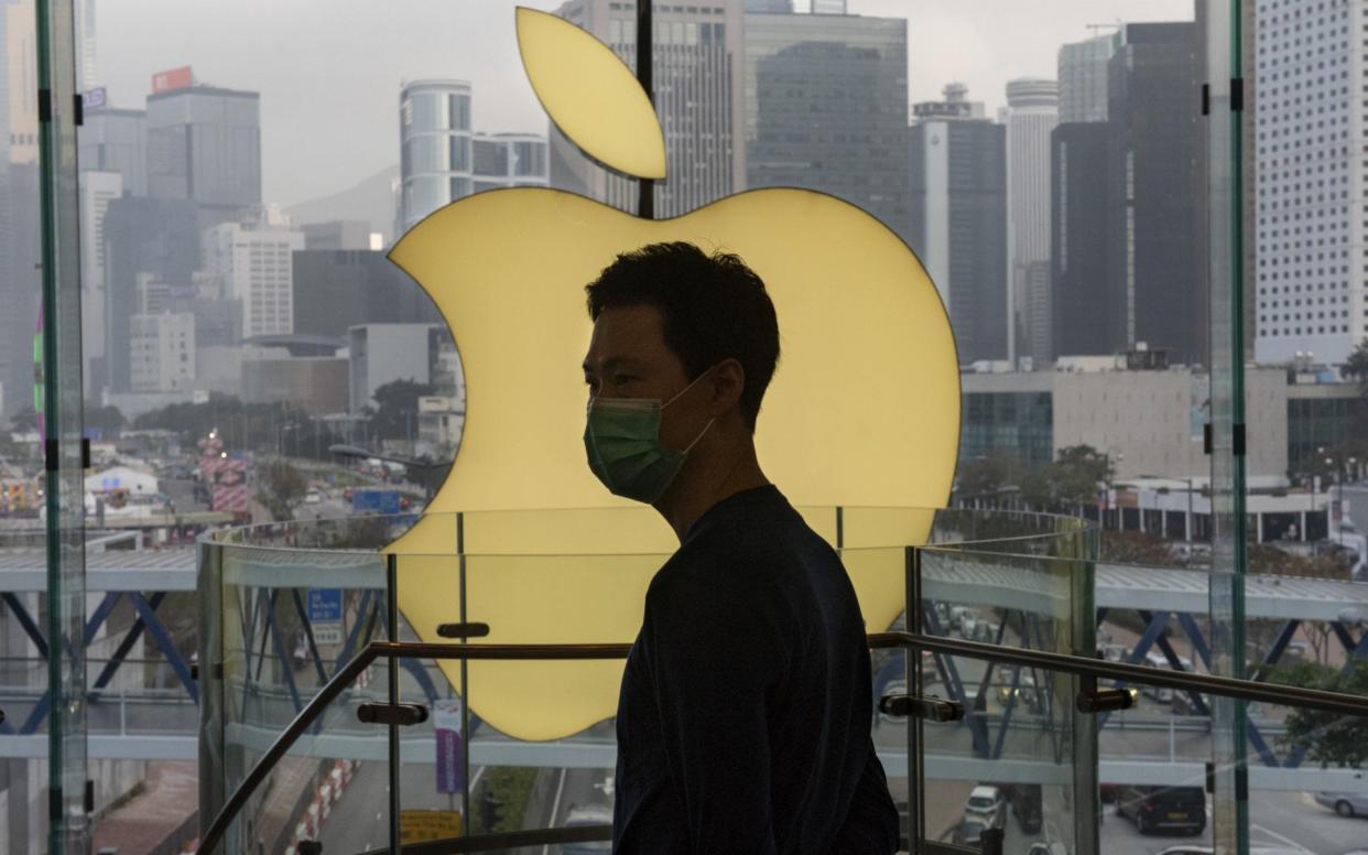 An employee stands in front of an Apple store logo in Hong Kong, where the company has been accused of assisting the Chinese government - Budrul Chukrut/Getty/Barcroft