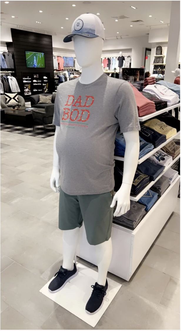 A mannequin with a gut wearing a "Dad Bod" T-shirt, knee-length shorts, and cap