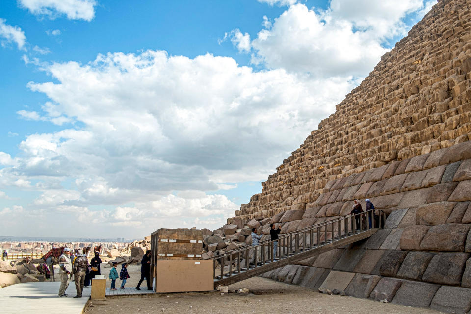 Visitors pose for a picture by the base of the Pyramid of Menkaure at the Giza Pyramids Necropolis, west of Cairo, Jan. 29, 2024. / Credit: KHALED DESOUKI/AFP/Getty
