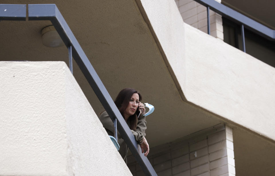 U.S. citizen Michelle Parker talks on her phone as she poses for a photo on the balcony at her home in Sydney on Oct. 20, 2020. Parker is a flight attendant and Australia considers her an essential worker who flies between her Sydney home and San Francisco. But New South Wales state's added layer of strict quarantine rules meant that when she was returning to her husband and children in Sydney for days, she was no longer considered an essential worker but a traveler who was expected to pay 3,000 Australian dollars ($2,100) to quarantine in a Sydney hotel for two weeks. (AP Photo/Rick Rycroft)