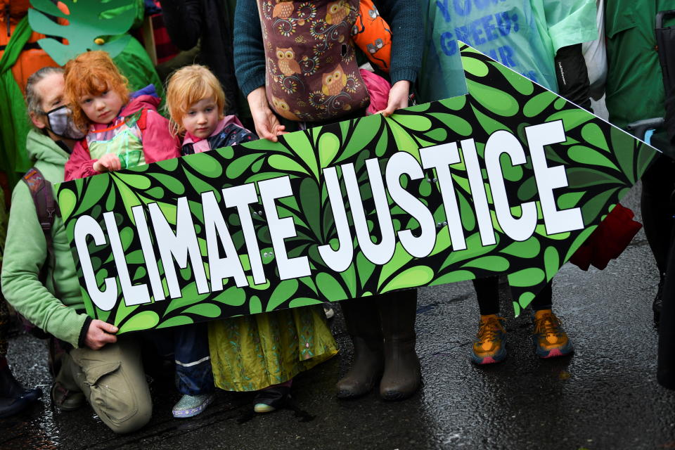 Climate activists, including children, hold an arrow-shaped sign that reads: Climate justice.