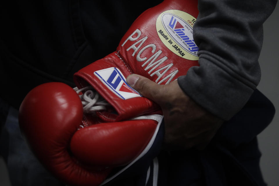 A trainer holds boxer Manny Pacquiao's gloves with Pacquiao's nickname embroidered on them at the Wild Card Boxing Club Monday, Jan. 14, 2019, in Los Angeles. The Filipino legend is in the winter of his career, gearing up for what could be one big last fight. Saturday's bout versus Broner isn't it, but Pacquiao trains with the knowledge that a second megafight against Floyd Mayweather could possibly be just months away if all goes well. (AP Photo/Jae C. Hong)