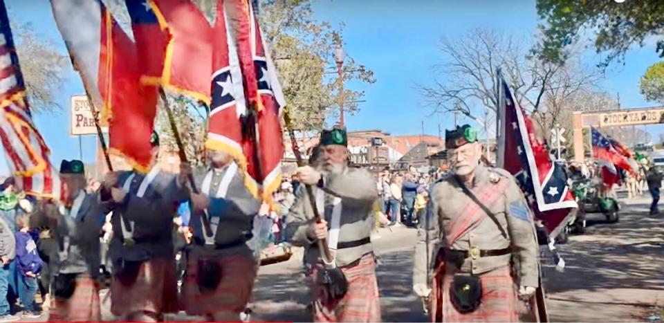 Sons of Confederate Veterans marchers carry the Southern Cross “battle flag” and other flags ahead of a wagon distributing battle flags in the Cowtown Goes Green parade March 18, 2023, in Fort Worth.