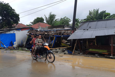 Residents ride a motorcycle past collapsed small shops after a tsunami hit Carita beach in Pandeglang, Banten province, Indonesia, December 23, 2018. REUTERS/Adi Kurniawan