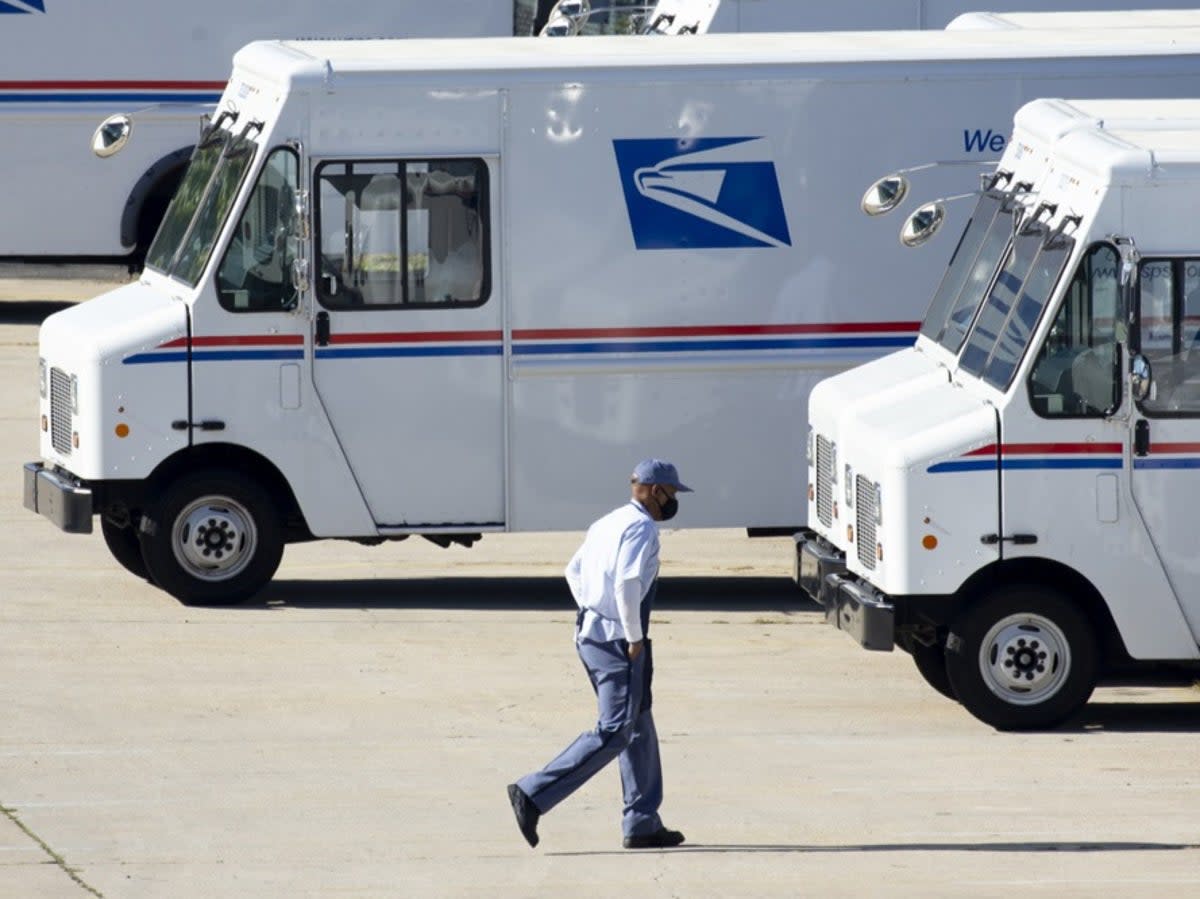 A mail carrier walks to a truck at a United States Postal Service (USPS) processing and distribution center in Washington, DC, on 8 October 2020 (EPA-EFE/Michael Reynolds)
