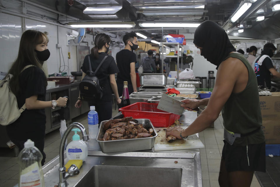 Protestors wear face masks as they cook meals for fellow protestors in a canteen at Hong Kong Polytechnic University in Hong Kong, Thursday, Nov. 14, 2019. Hong Kong residents endured traffic snarls and mass transit disruptions Thursday as protesters closed some main roads and rail networks while police skirmished with militant students at major universities. (AP Photo/Kin Cheung)