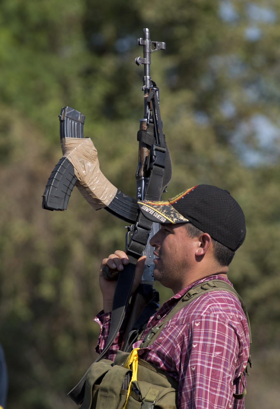 An armed man belonging to the Self-Defense Council of Michoacan, (CAM), stands guard at checkpoint at the entrance of Antunez, Mexico, Tuesday, Jan. 14, 2014. The Mexican government moved in to quell violence between vigilantes and a drug cartel, and witnesses say several unarmed civilians were killed in an early Tuesday confrontation. (AP Photo/Eduardo Verdugo)