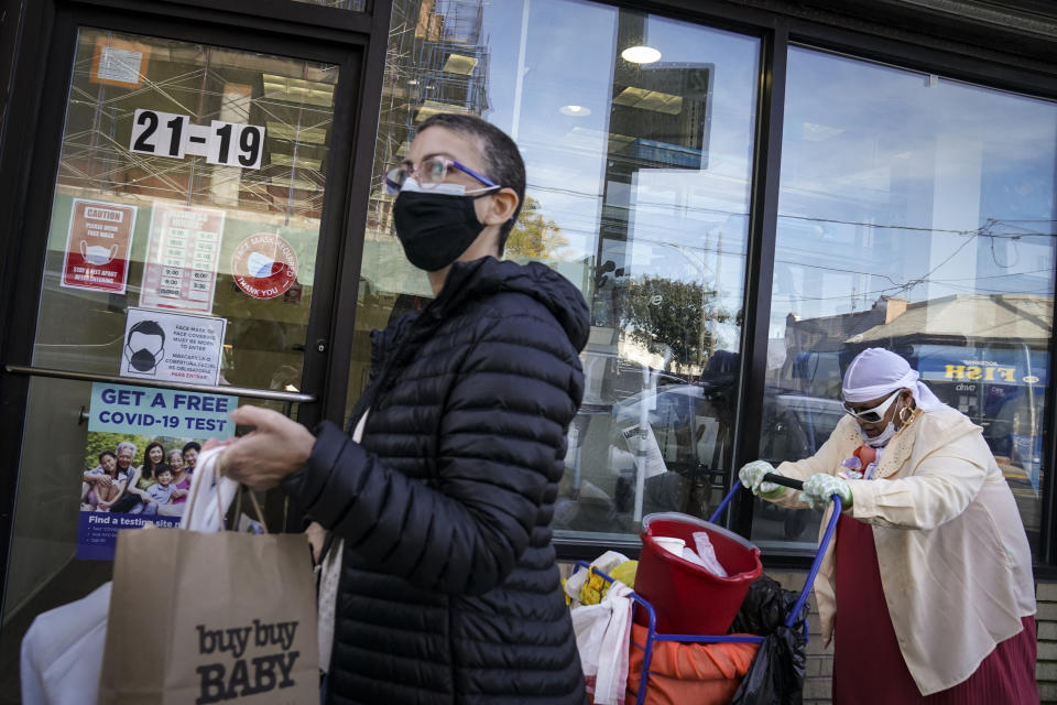 Pedestrians in protective masks pass a storefront on Thursday, Oct. 15, 2020, as restrictions on operations are imposed due to an increase in COVID-19 infections in the Far Rockaway neighborhood of the borough of Queens in New York. After shutdowns swept entire nations during the first surge of the coronavirus earlier this year, some countries and U.S. states are trying more targeted measures as cases rise again around the world. New York’s new round of shutdowns zeroes in on individual neighborhoods, closing schools and businesses in hot spots measuring just a few square miles. (AP Photo/John Minchillo)