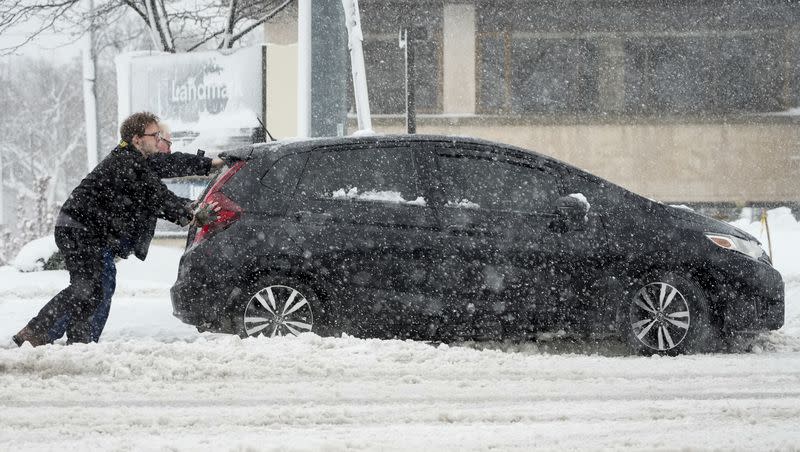People push a car out of a snowbank as a winter storm arrives on Friday, Jan. 12, 2024, in West Allis, Wis.