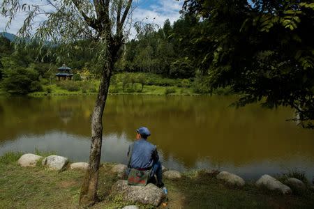 A participant dressed in a replica red army uniform sits at a lake during a break in a Communist team-building course extolling the spirit of the Long March in the mountains outside Jinggangshan, Jiangxi province, China, September 14, 2017. REUTERS/Thomas Peter