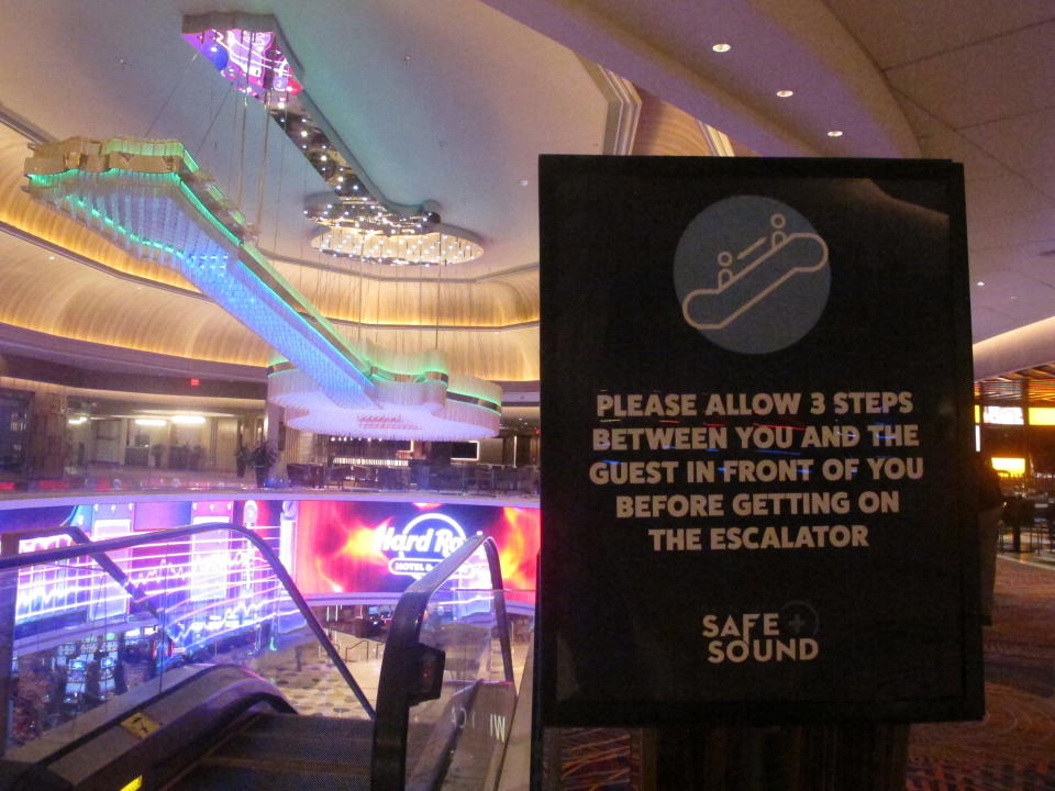 This June 24, 2020 photo shows a sign in the Hard Rock casino in Atlantic City N.J. instructing customers to maintain a distance on the escalator to prevent the spread of the coronavirus. Smoking, drinking and eating will all be prohibited when Atlantic City's casinos reopen after being shut for three months due to the coronavirus outbreak under rules imposed by New Jersey Gov. Phil Murphy on June 29, 2020. (AP Photo/Wayne Parry)