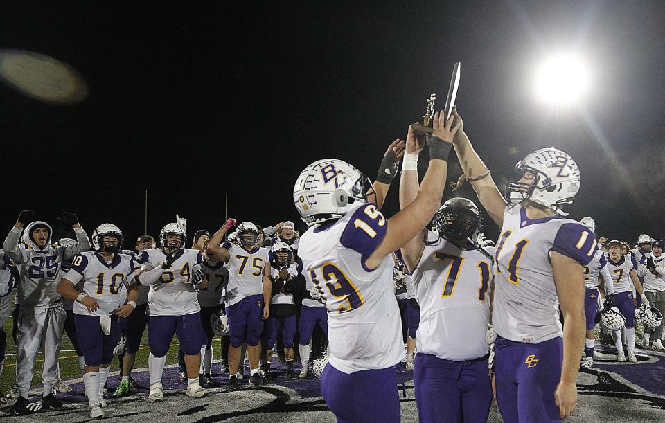 Bloom-Carroll's Chase Plantz, Kale Kraner and Andrew Marshall hold up the regional championship trophy following the Bulldogs' 33-28 win over Watterson in the Division III Regional Final game at DeSales on Nov. 18.