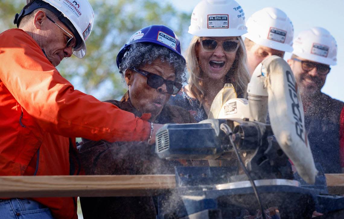 Opal Lee, center, cuts a wood board for the construction of her new home with the help of Fort Worth Mayor Mattie Parker, right, and Trinity Habitat of Humanity CEO Gage Yager, left, on Thursday, March 21, 2024, in Fort Worth. Texas Capital, Habitat for Humanity and HistoryMaker Homes joined together to help Lee rebuild a home on the same lot that her family had a home on. In 1939 a white mob drove her family from the home and set fire to it.