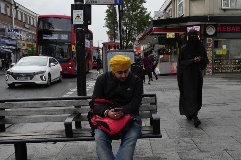 A man sits on a bench in the district of Southall in London, Tuesday, Sept. 13, 2022. In a church in a West London district known locally as Little India, a book of condolence for Queen Elizabeth II lies open. Five days after the monarch’s passing, few have signed their names. The congregation of 300 is made up largely of the South Asian diaspora, like the majority of the estimated 70,000 people living in the district of Southall, a community tucked away in London's outer reaches of London and built on waves of migration that span 100 years. (AP Photo/Kin Cheung)