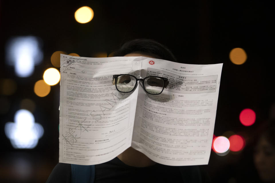 A protester wearing a mask made out of a government form attends a protest in Hong Kong, Friday, Oct. 18, 2019. Hong Kong pro-democracy protesters are donning cartoon and superhero masks as they formed a human chain across the semiautonomous Chinese city, in defiance of a government ban on face coverings. (AP Photo/Mark Schiefelbein)