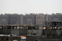 Workers stand on a building under construction in the New Administrative Capital (NAC), east of Cairo