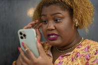 Krystina Francois, a child of Haitian immigrants to the U.S. and one of the co-founders along with Francesca Menes of the Black Collective, participates in a video call as she works outside a Starbucks, Tuesday, Sept. 21, 2021, in Miami Shores, Fla. Francois and Menes, whose advocacy organization focuses on the political needs and economic empowerment of Black people across the African diaspora, have called for the Biden administration to immediately suspend plans to remove migrants via planes bound for Haiti. (AP Photo/Rebecca Blackwell)