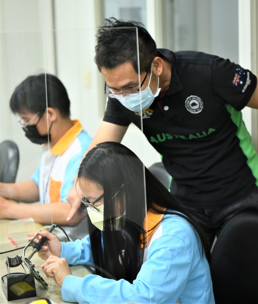徐昌旭訓練師(右)指導學生進行數位邏輯電路板焊接。(勞動力發展署北分署提供)
