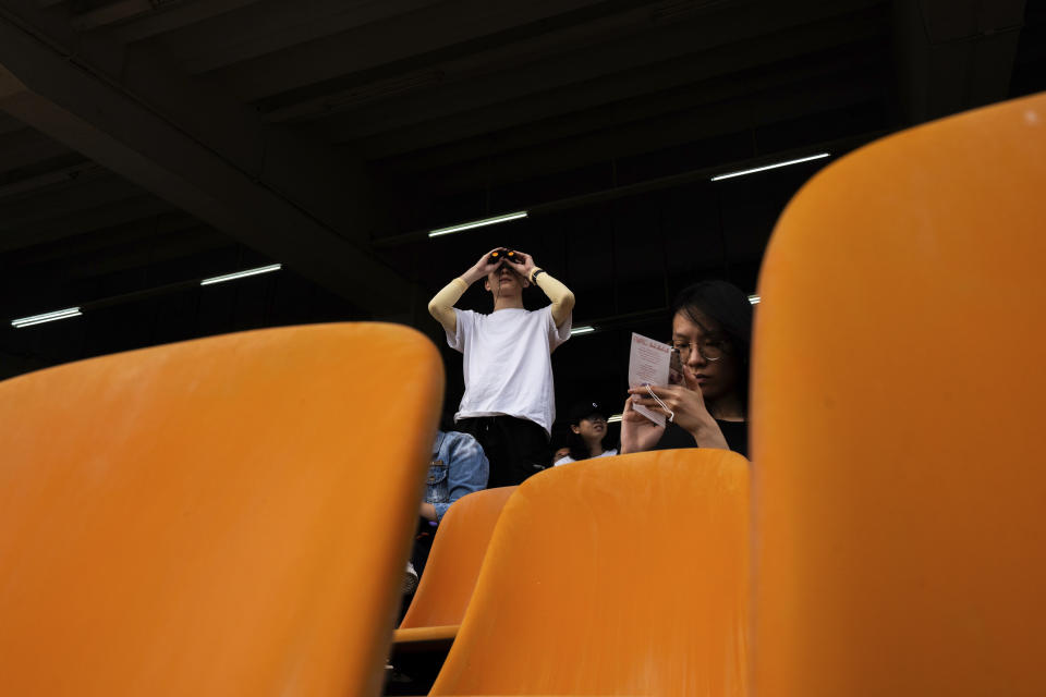 A visitor uses binoculars to watch a horse race at the Macao Jockey Club in Macao, Saturday, March 30, 2024. After more than 40 years, Macao’s horse racing track hosted its final races on Saturday, bringing an end to the sport in the city famous for its massive casinos. (AP Photo/Louise Delmotte)