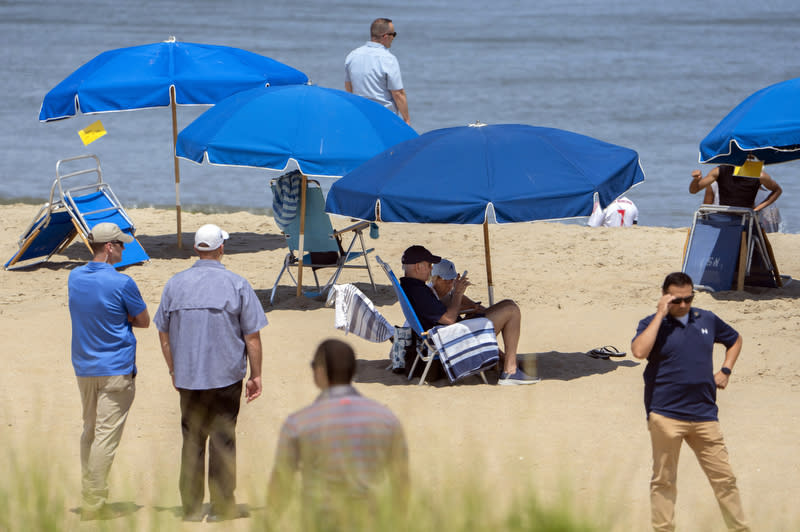 President Biden and first lady Jill Biden sit underneath an umbrella