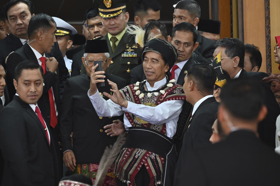 Indonesian President Joko Widodo, wearing traditional attire from Tanimbar Islands of Maluku province, uses a mobile phone to take photos after delivering his State of the Nation Address ahead of the country's Independence Day, at the parliament building in Jakarta, Indonesia, Wednesday, Aug. 16, 2023. (Adek Berry/Pool Photo via AP)
