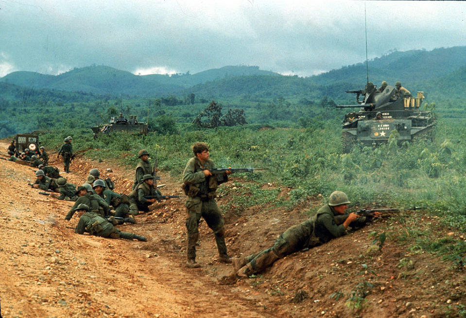 During a skirmish, two American soldiers fire their guns at enemy positions, while other soldiers, including South Vietnamese regulars, take cover in a shallow ditch by the side of a dirt road, near Dak To, Vietnam, mid 1969. The US tank at right is an M42A1 'Duster.' (Photo by Larry Burrows/The LIFE Picture Collection via Getty Images)