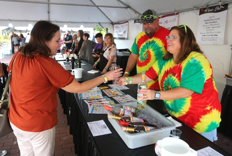 Angela Krendick, left, is served a glass of wine by Nate Mayle, center, and Anna Mayle, right, of Easley Winery during Vintage Canton on Thursday, Sept. 15, 2022.