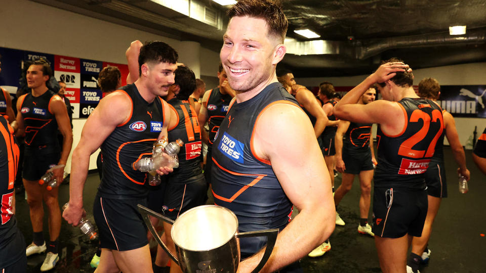 GWS Giants player Toby Greene celebrates as teammates stand in the background.