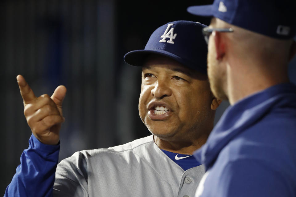 Los Angeles Dodgers manager Dave Roberts, left, talks to a member of his staff between innings of a baseball game against the New York Mets, Sunday, Sept. 15, 2019, in New York. (AP Photo/Kathy Willens)