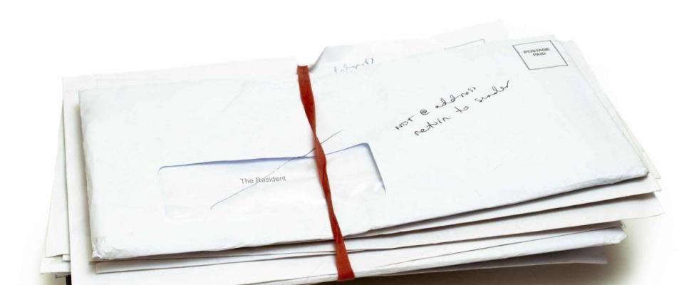 Bundle of mail marked return to sender on white background.