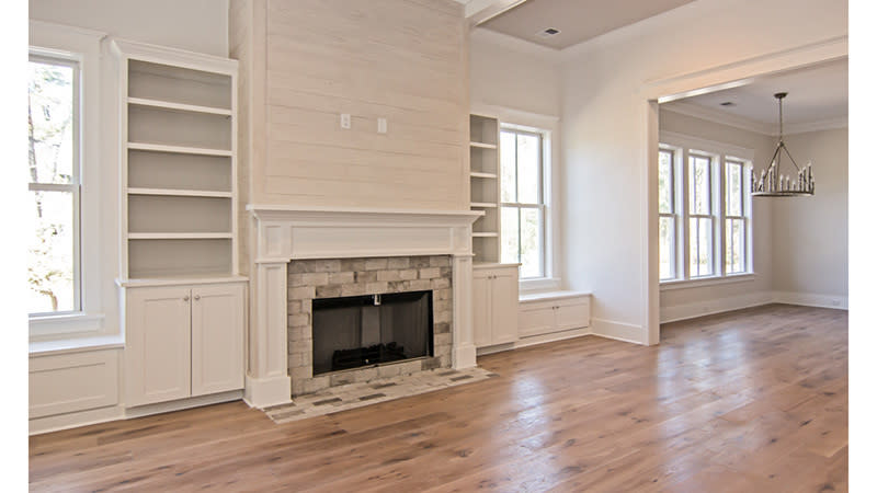 <p>In the living room, the fireplace is flanked by two shelving units. Arrange family photos on the shelves above, and stow board games in the cabinets below. </p>