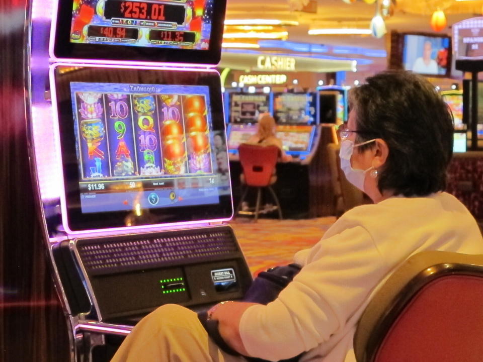 A gambler wears a mask while playing a slot machine at the Hard Rock casino in Atlantic City, N.J, on July 2, the day it reopened after being closed for 3 1/2 months due to the coronavirus outbreak. Figures released on April 9, 2021, showed Atlantic City's nine casinos collectively saw their gross operating profits decline by more than 80% in 2020 amid the pandemic. (AP Photo/Wayne Parry)