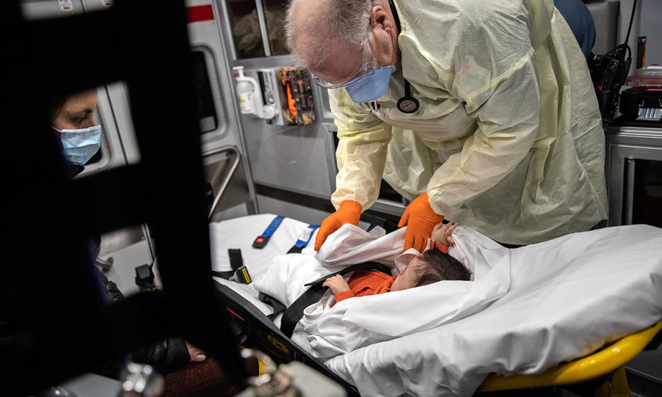 Paramedic Randy Lilly, wearing personal protection equipment (PPE), tends to a 10-month-old boy with fever while riding by ambulance with the infant’s mother to Stamford Hospital in Stamford, Connecticut. (John Moore/Getty Images)