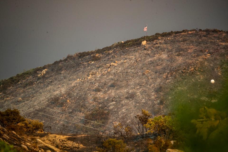 An American flag is seen atop a burnt hill having survived the Highland Fire in Banning, Calif., Friday, July 14, 2023. 