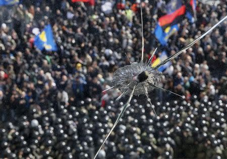 A broken window of parliament building is seen as radical protesters clash with Interior Ministry and law enforcement members on the Day of Ukrainian Cossacks, marked by activists and supporters of the All-Ukrainian Union Svoboda (Freedom) Party and far-right activists and nationalists to honour the role of the movement in the history of Ukraine, during a rally near the parliament building in Kiev, October 14, 2014. REUTERS/Gleb Garanich