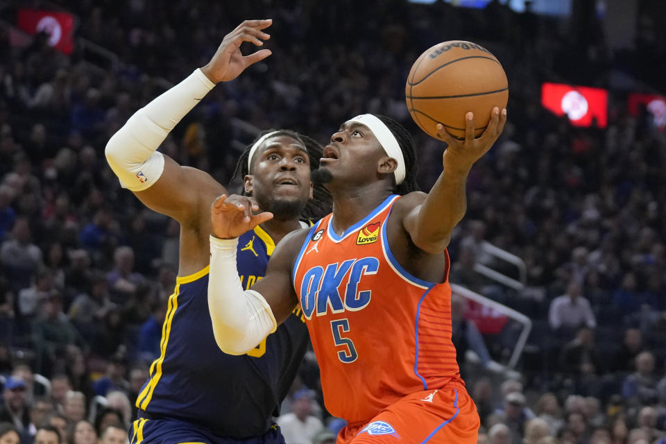 Oklahoma City Thunder guard Luguentz Dort, right, drives to the basket against Golden State Warriors forward Kevon Looney during the first half of an NBA basketball game in San Francisco, Tuesday, April 4, 2023. (AP Photo/Jeff Chiu)