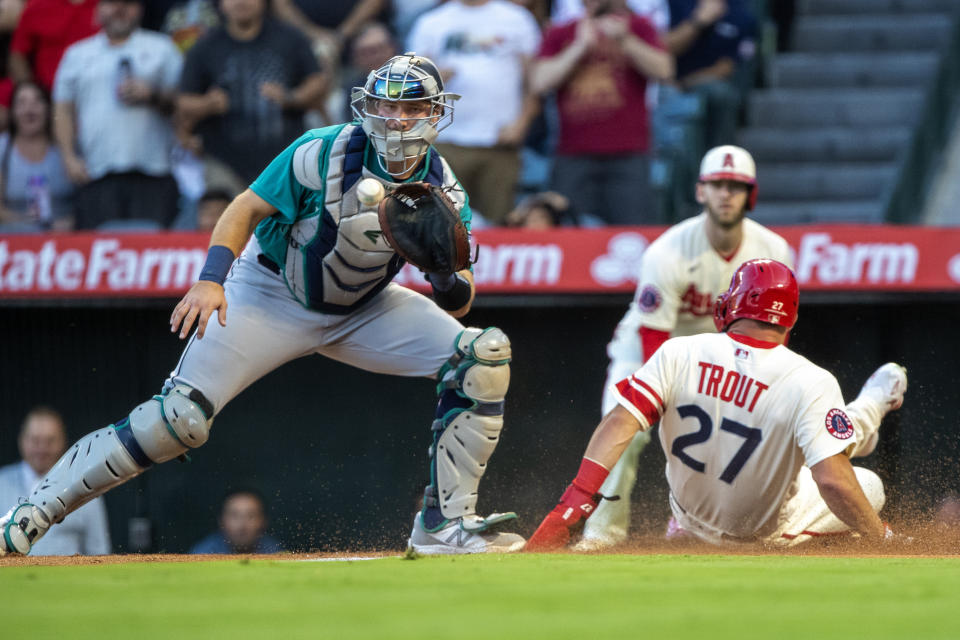 Los Angeles Angels' Mike Trout, right, beats the throw to Seattle Mariners catcher Cal Raleigh to score on a double by Shohei Ohtani during the first inning of a baseball game in Anaheim, Calif., Saturday, Sept. 17, 2022. (AP Photo/Alex Gallardo)