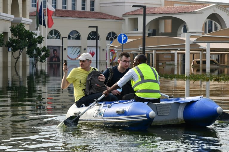 A staff member transports guests on an inflatable boat to the entrance of a hotel engulfed in flood water in Dubai on April 22, 2024. (Giuseppe CACACE)